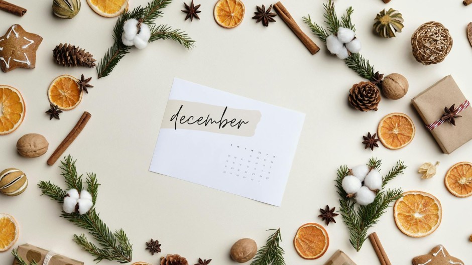Paper December calendar surrounded by pine cones, dried orange slices, and cinnamon sticks.