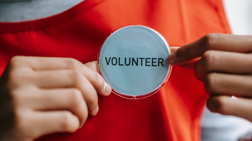Close up of a person holding volunteer badge.
