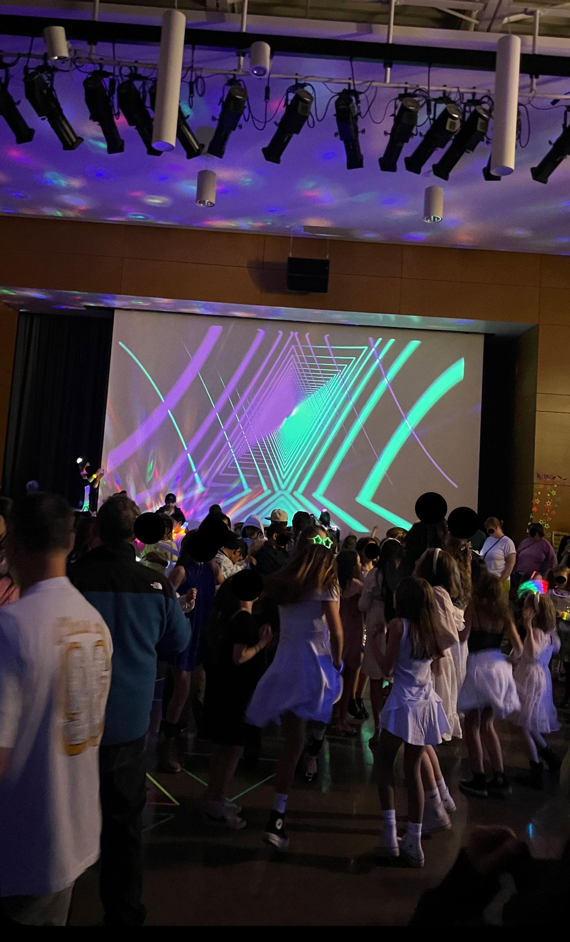 Hazel Wolf K-8 students dance in the darken cafeteria while laser designs project on the screen.