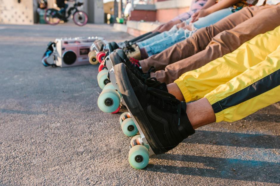 Four people display their roller skates in a line.
