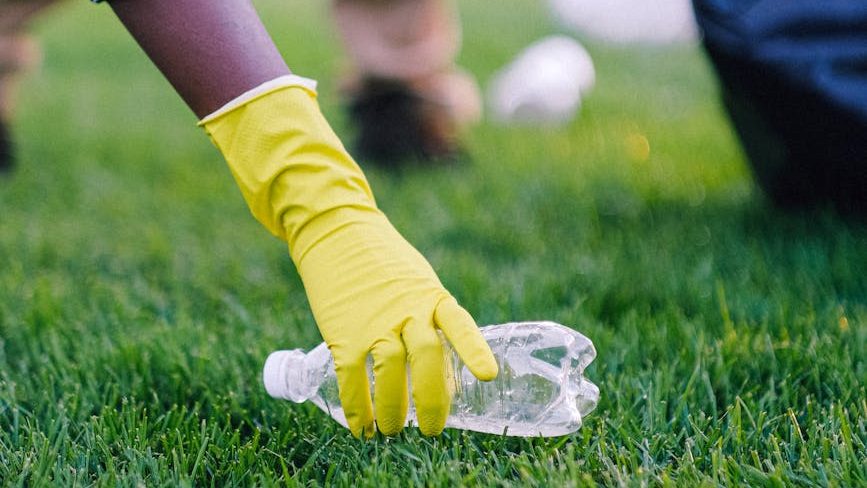 a hand wearing rubber gloves picks up a water bottle