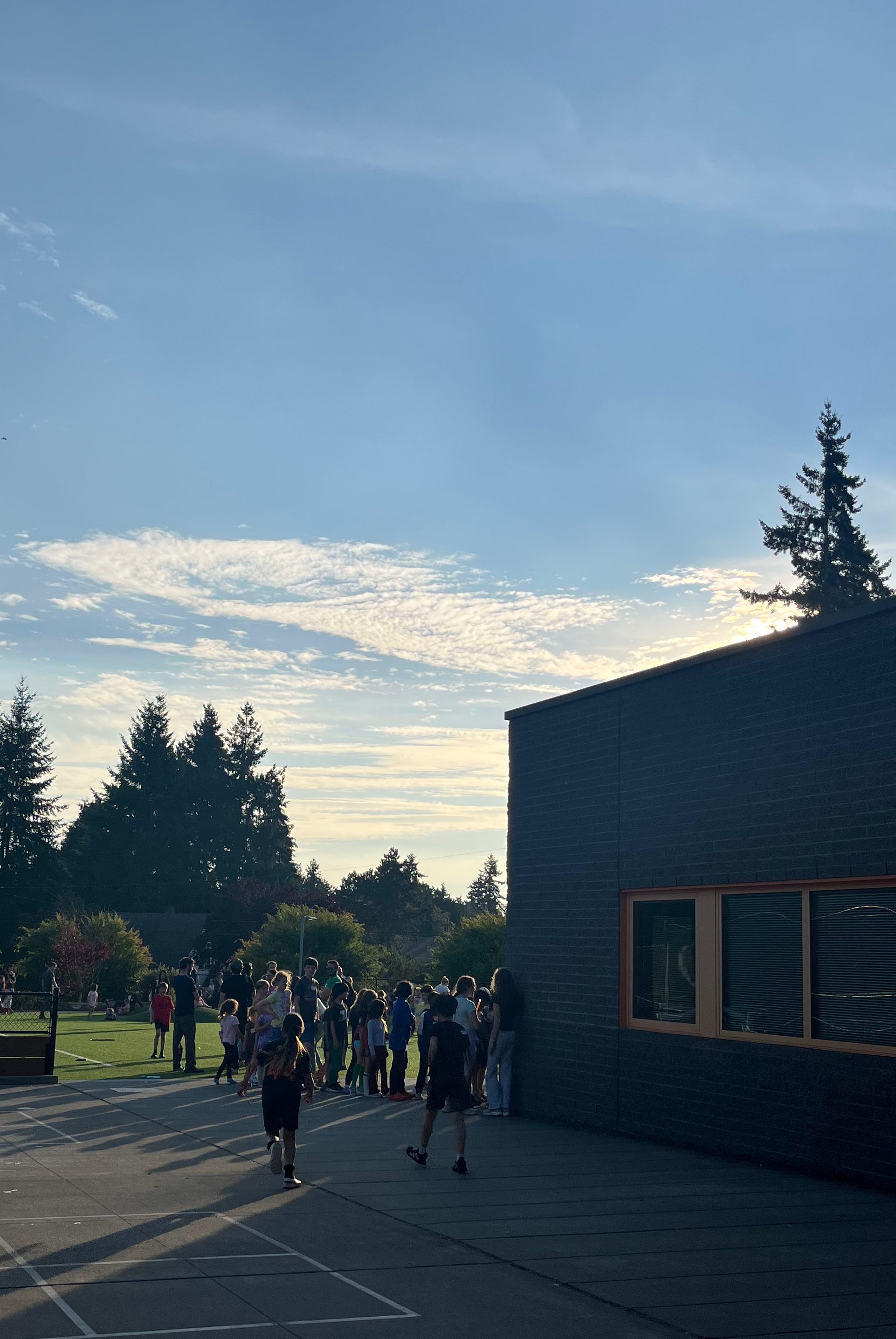 Kids running to line up for ice cream by school building.