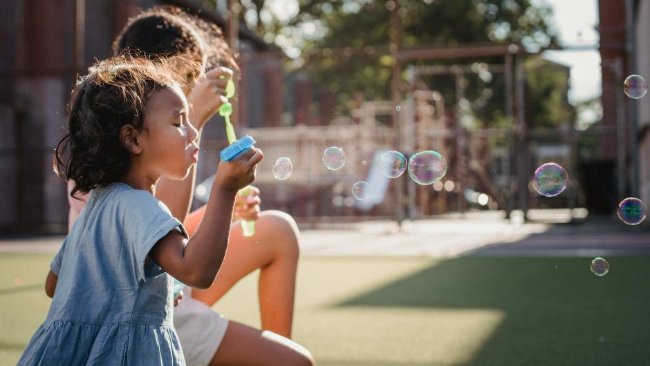 Young girl blows bubbles at a playground.